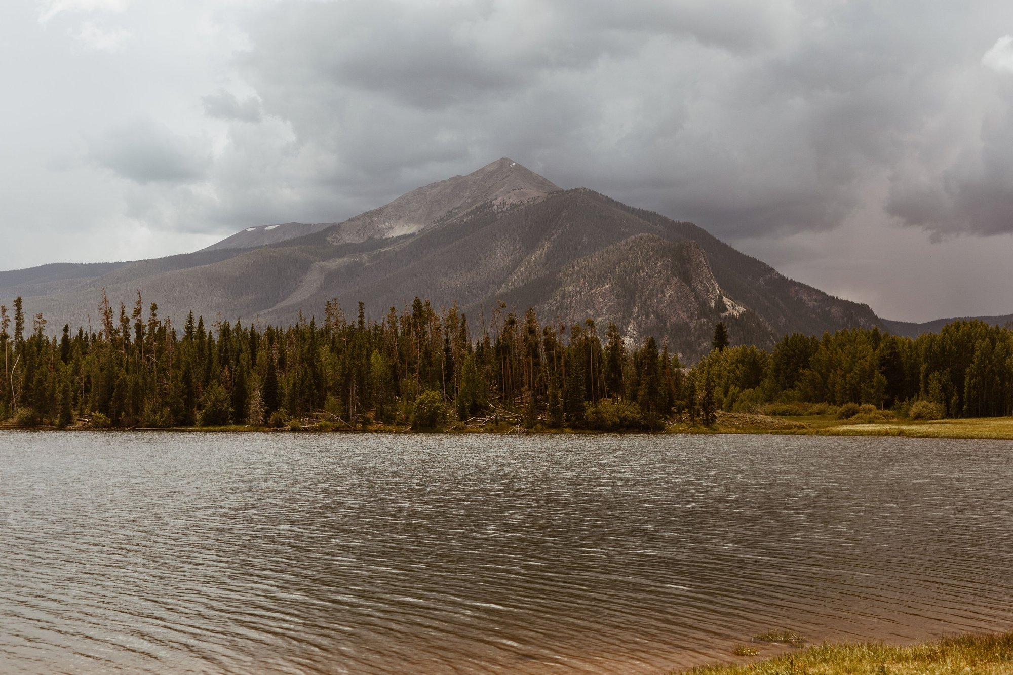 Storm clouds over a Colorado mountain above a rippling alpine lake