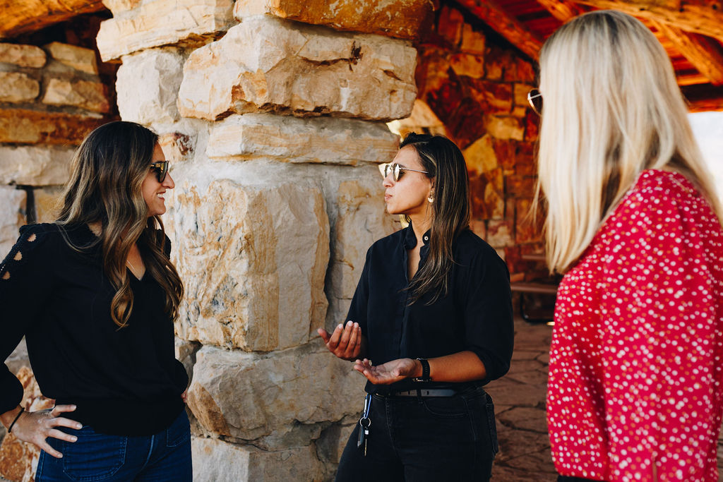 Three women in conversation under a stone pavilion in rural Colorado