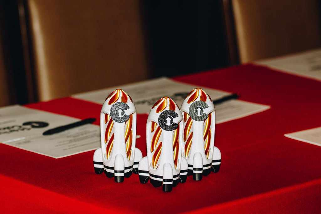 Three Colorado-flag rocket trophies on a red-draped table
